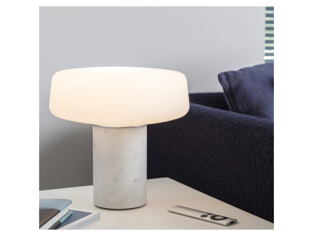 Terence Woodgate Solid Table Light Small - Carrara Marble turned on with Navy Sofa