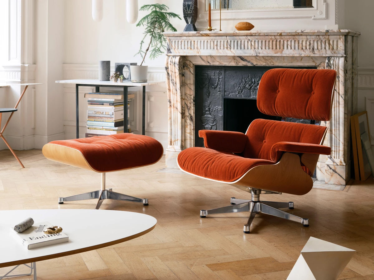 Vitra Eames lounge chair and ottoman  in Calma fabirc in a living room with a fireplace.