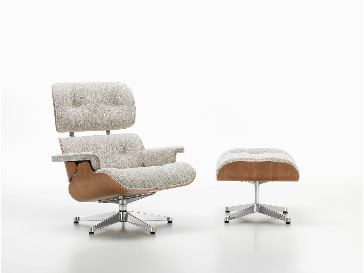 A Vitra Eames Lounge Chair and Ottoman in a  nubia fabric and a wooden shell.